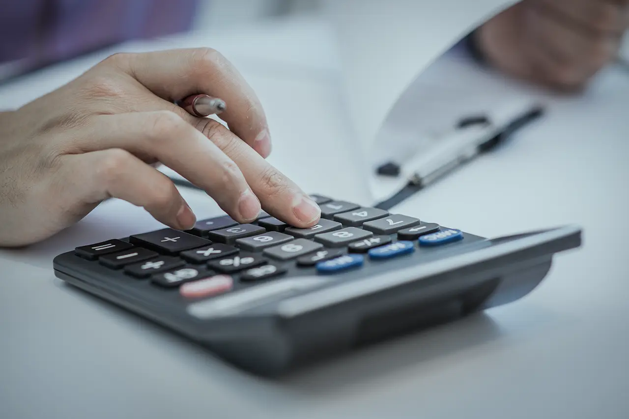 Manos usando una calculadora junto a documentos contables